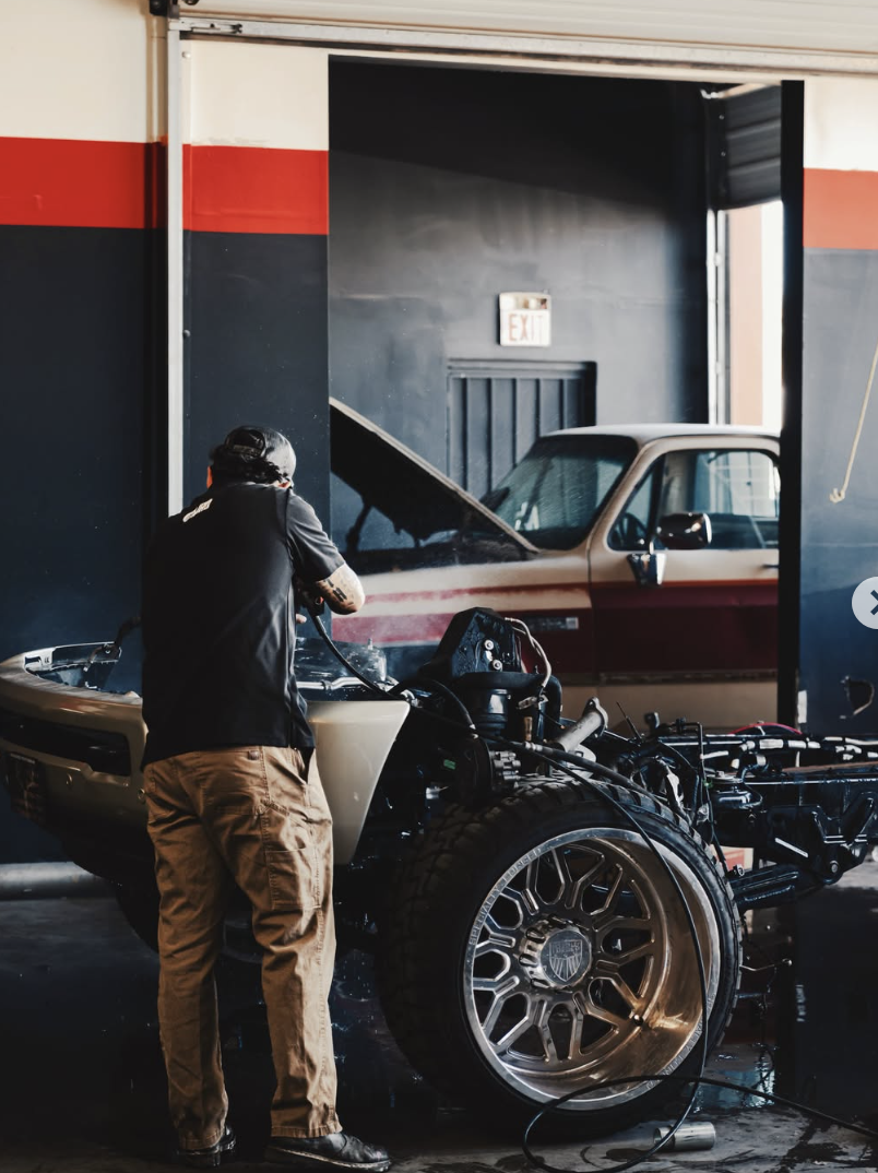 Technician working on a stripped truck chassis in the shop bay