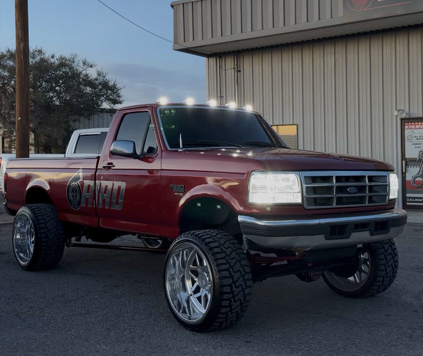 Red lifted OBS Ford F-150 with AIAID wrap outside the shop